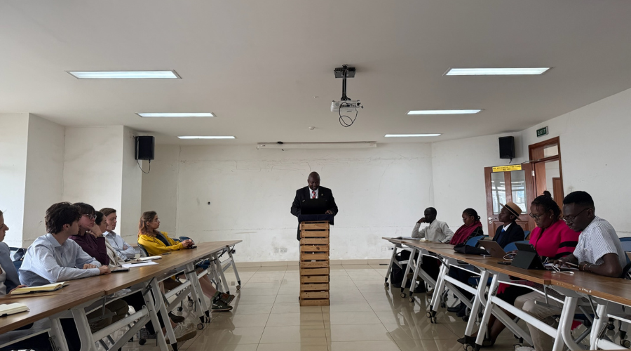 A photo of a speaker at a lectern at the front of a classroom. 