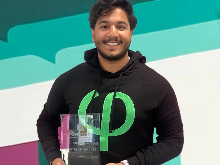 Akber Tahir stands holding an award from LSE Generate