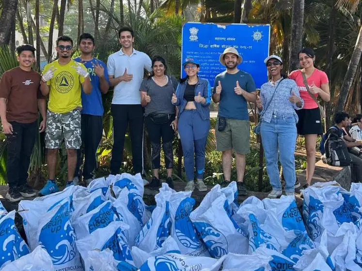 Alumni in Mumbai stand with large sacks after cleaning a local beach