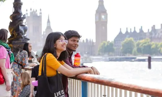 Two students look across the river Thames with Big Ben in the background