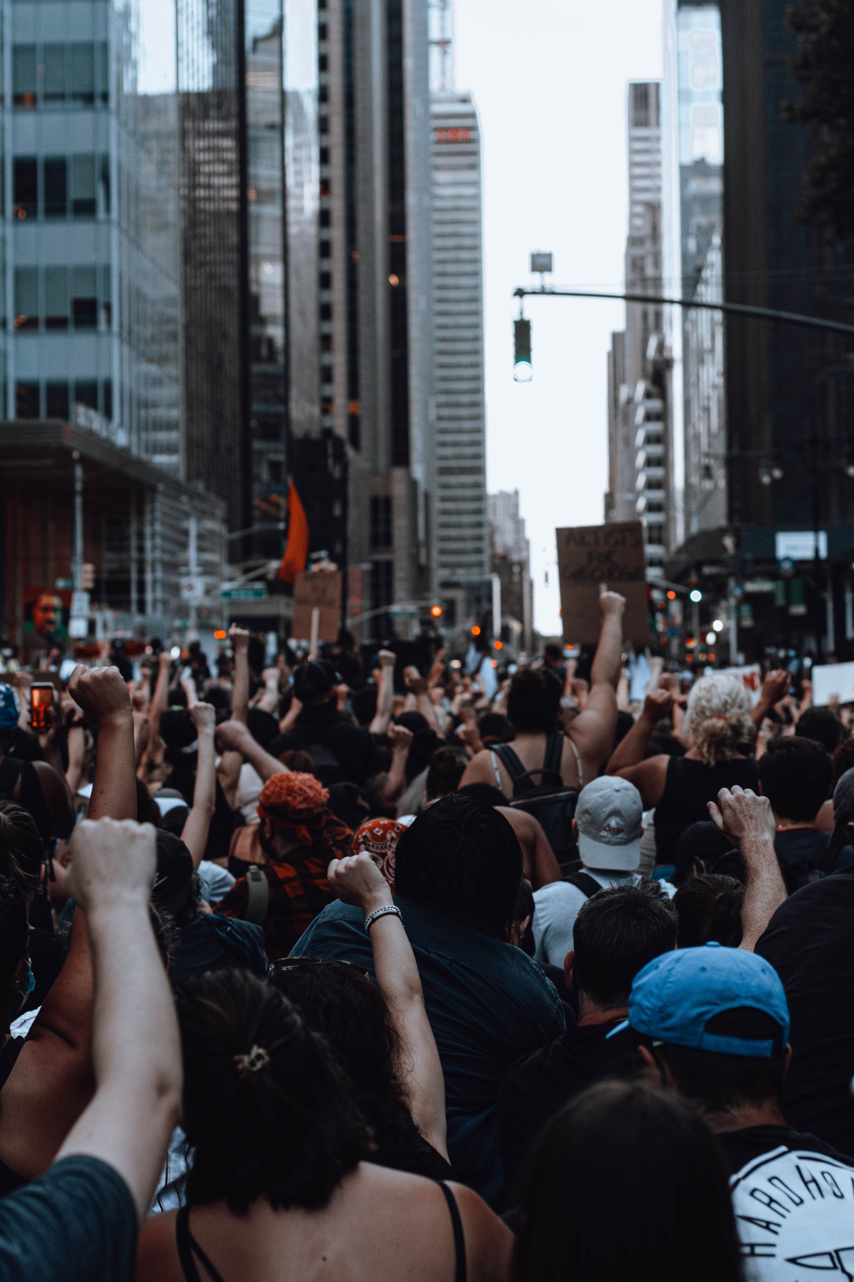 A crowd of people at a protest with raised fists, photographed from behind