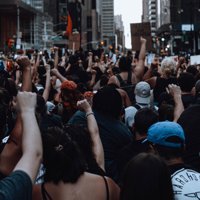 A crowd of people at a protest with raised fists, photographed from behind