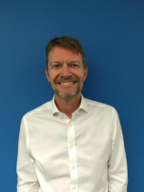 Headshot of a man in white shirt with blue background