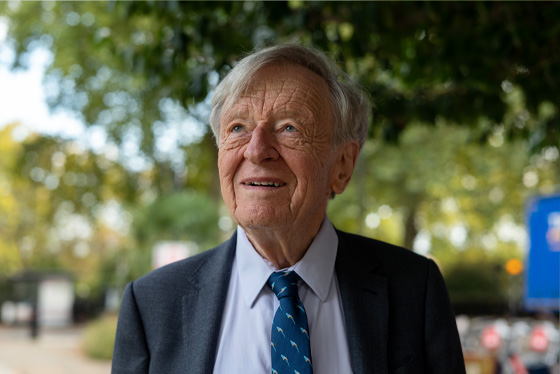 Lord Alf Dubs stands an area of greenery