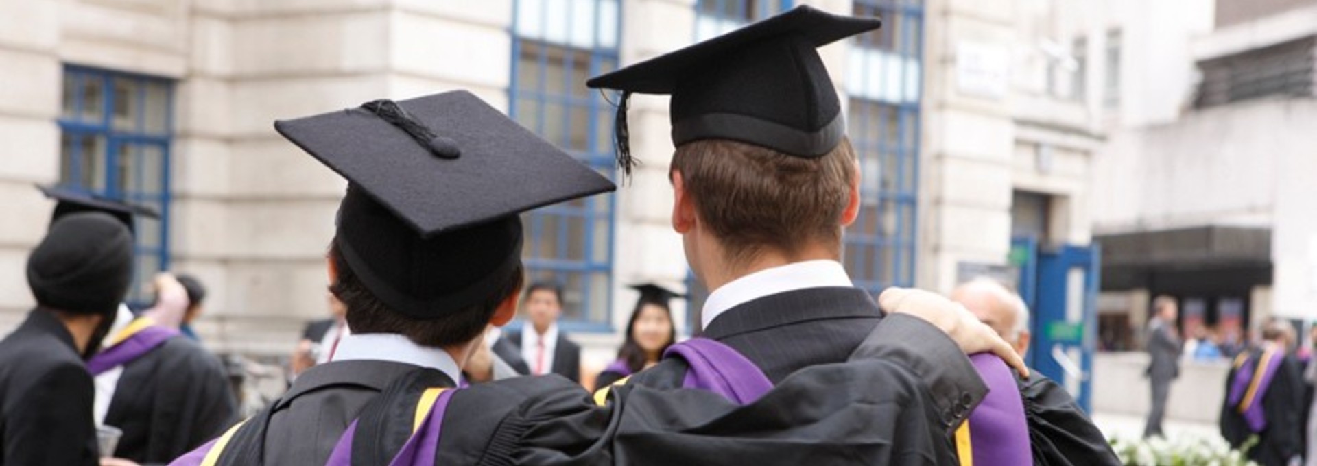 LSE graduates with arms around each other, back to camera.