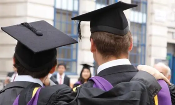 LSE graduates with arms around each other, back to camera.