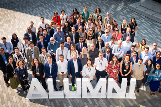 LSE alumni gather around large white letters that spell Alumni