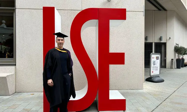 Alumnus Roberto Napolitano standing in front of red LSE letters