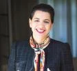 Headshot of a woman with brown hair with a colorful scarf and a work jacket