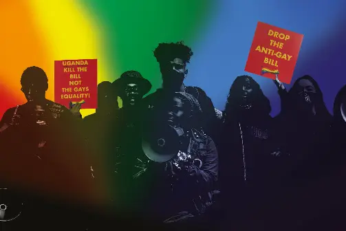 A crowd of people with protest signs that say 'Drop the anti-gay bill' and 'Uganda kill the bill'.
