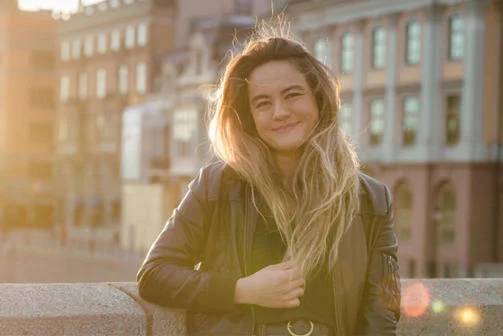 April stands on a bridge at sunset