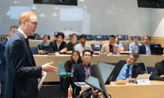 A man in a suit speaks to a lecture theatre.