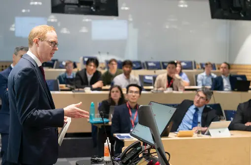 A man in a suit speaks to a lecture theatre.
