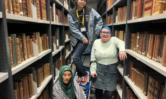 Three people posing between two book shelves