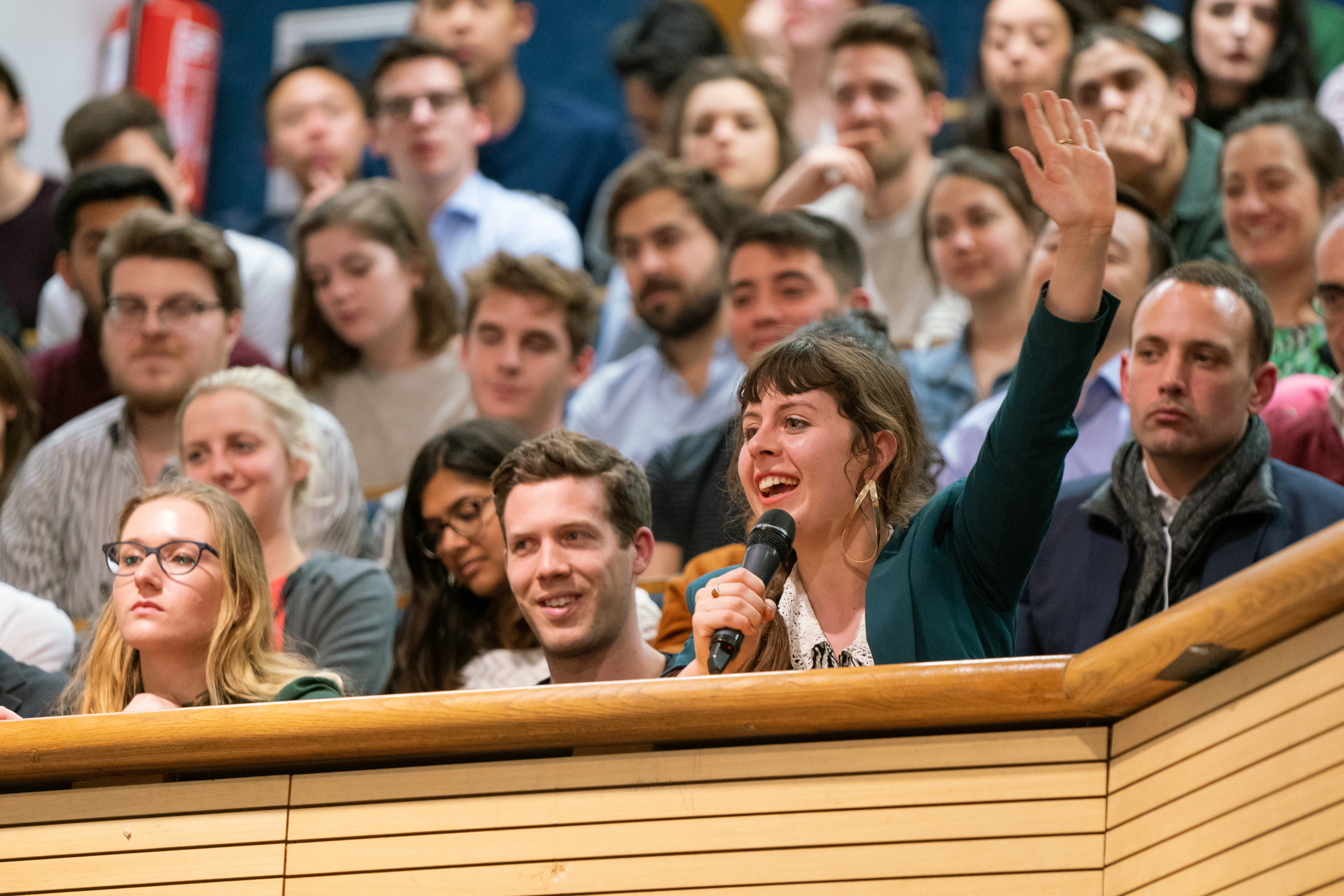Smiling audience member with microphone raising hand