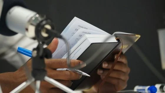 A person holding a notebook while recording a podcast.