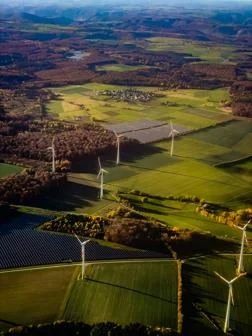 Aerial shot of fields with wind turbines and solar panels on