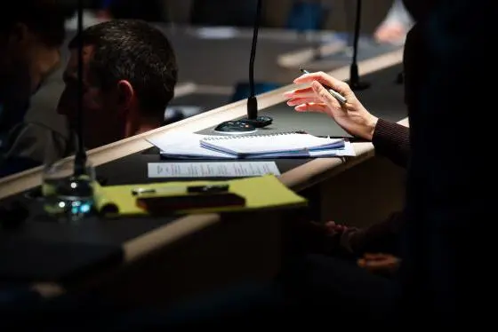Hand poised with pen over notebook