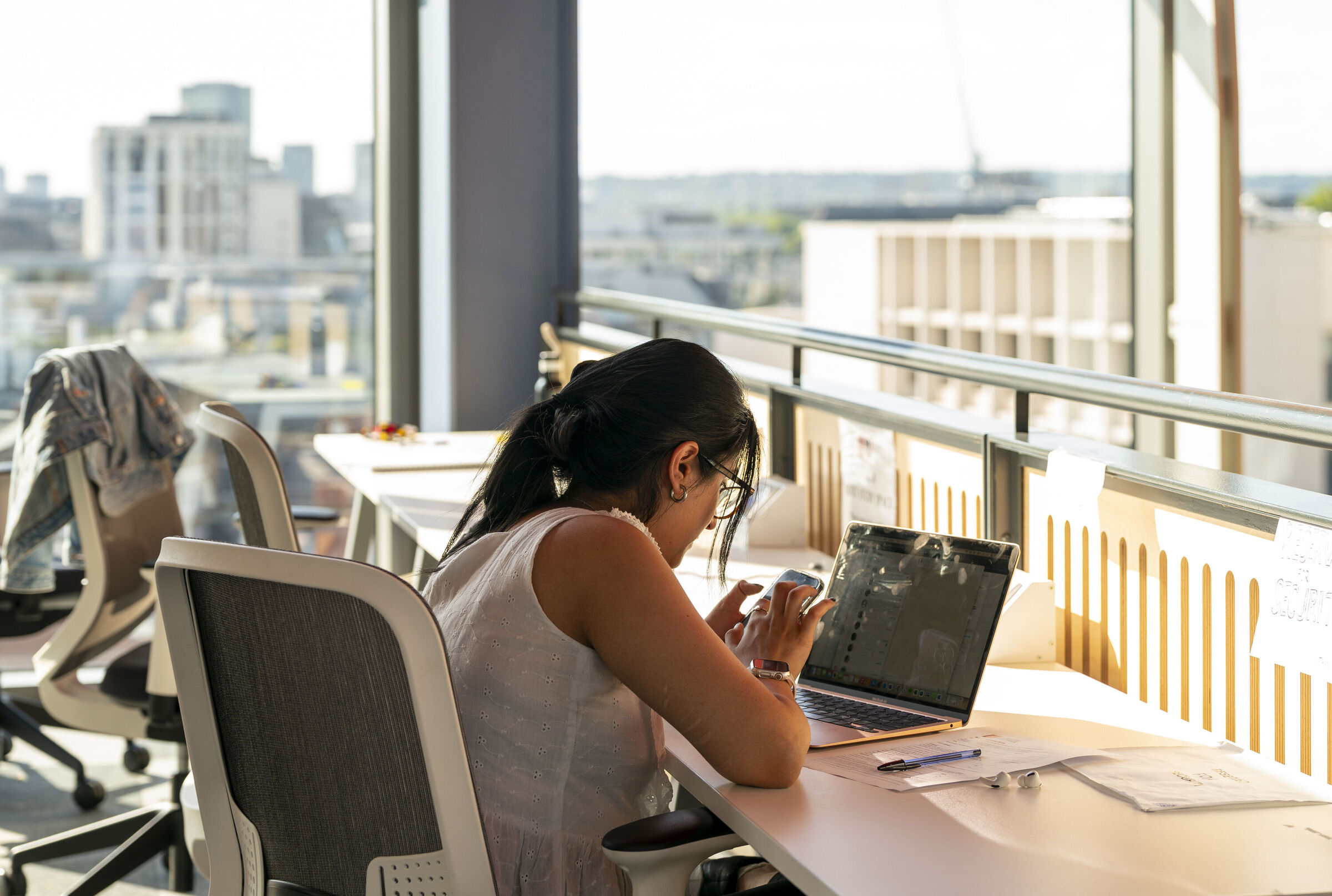 An LSE student in the Centre Building (CBG) working on assignments on her laptop and phone
