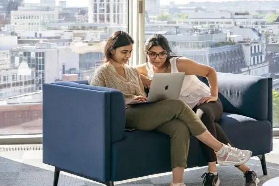 Students on a sofa looking at a laptop.
