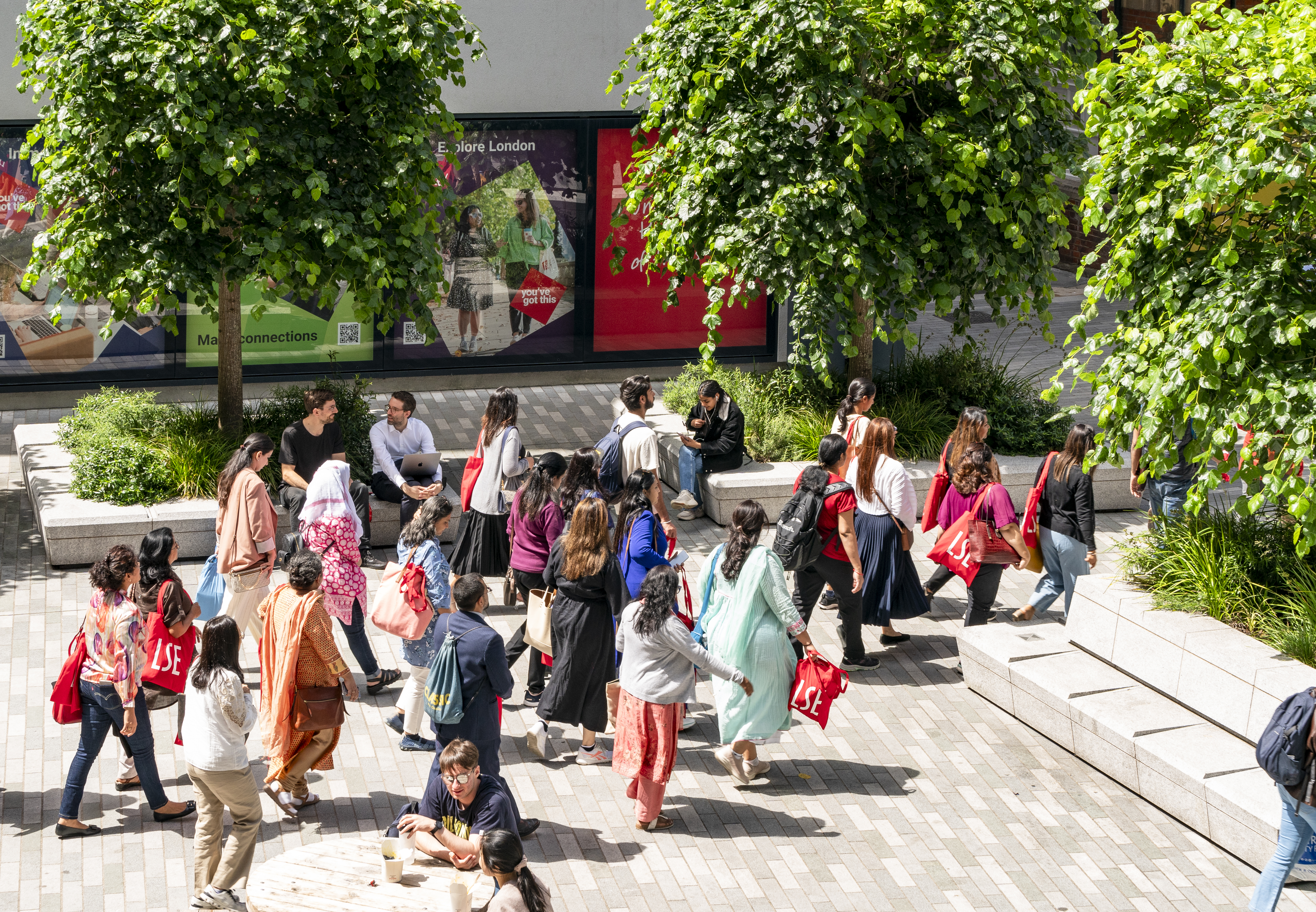 Students walking across campus with LSE tote bags