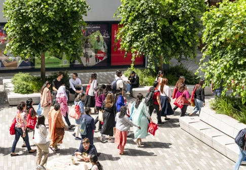 Students walking across campus with LSE tote bags