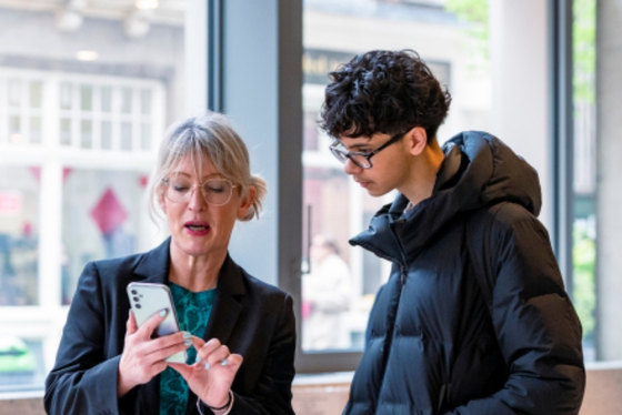 A member of the careers team supporting an LSE alum at a careers event, showing resources and information on a phone.