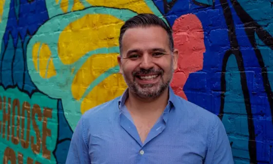 Headshot of Carlos Miranda in front of a colourful wall