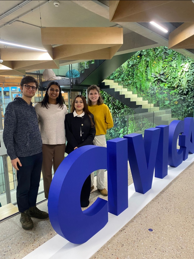 4 student ambassadors standing behind large blue CIVICA sign