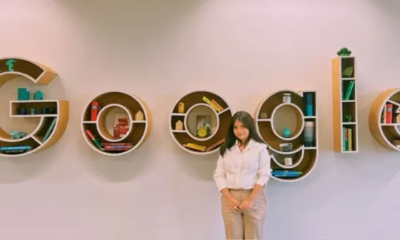 A student posing with shelves spelling Google