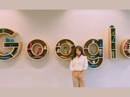 A student posing with shelves spelling Google