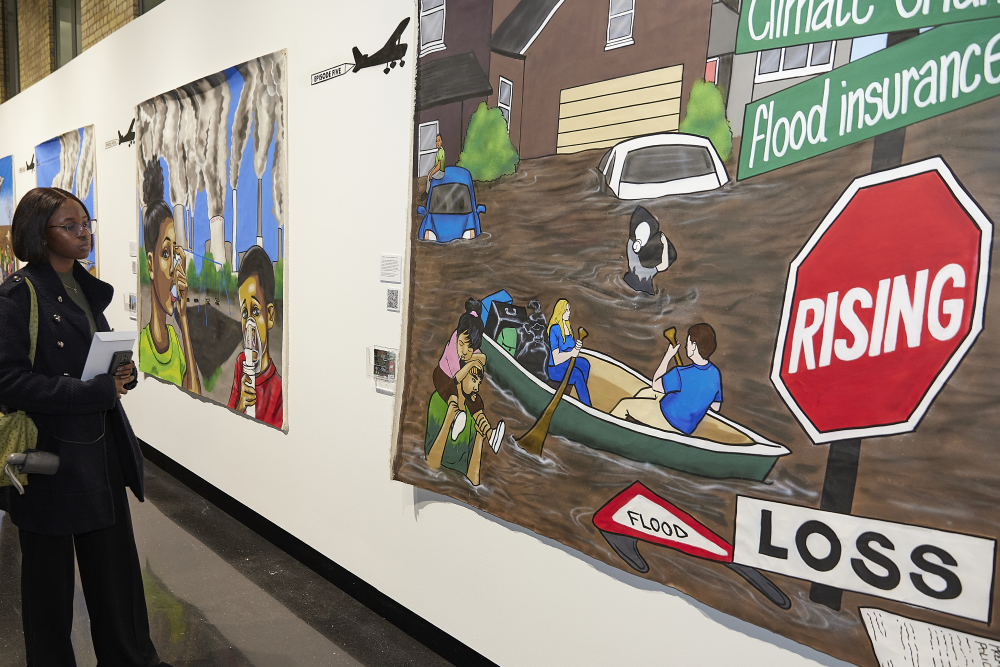 An attendee at an exhibition on climate change looking at a canvas image of flooding in the US