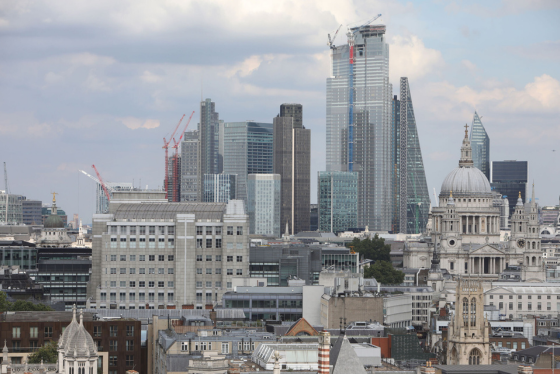Aerial view of London skyline showing historic St Paul's Cathedral alongside modern City of London skyscrapers under construction.