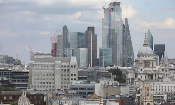 Aerial view of London skyline showing historic St Paul's Cathedral alongside modern City of London skyscrapers under construction.