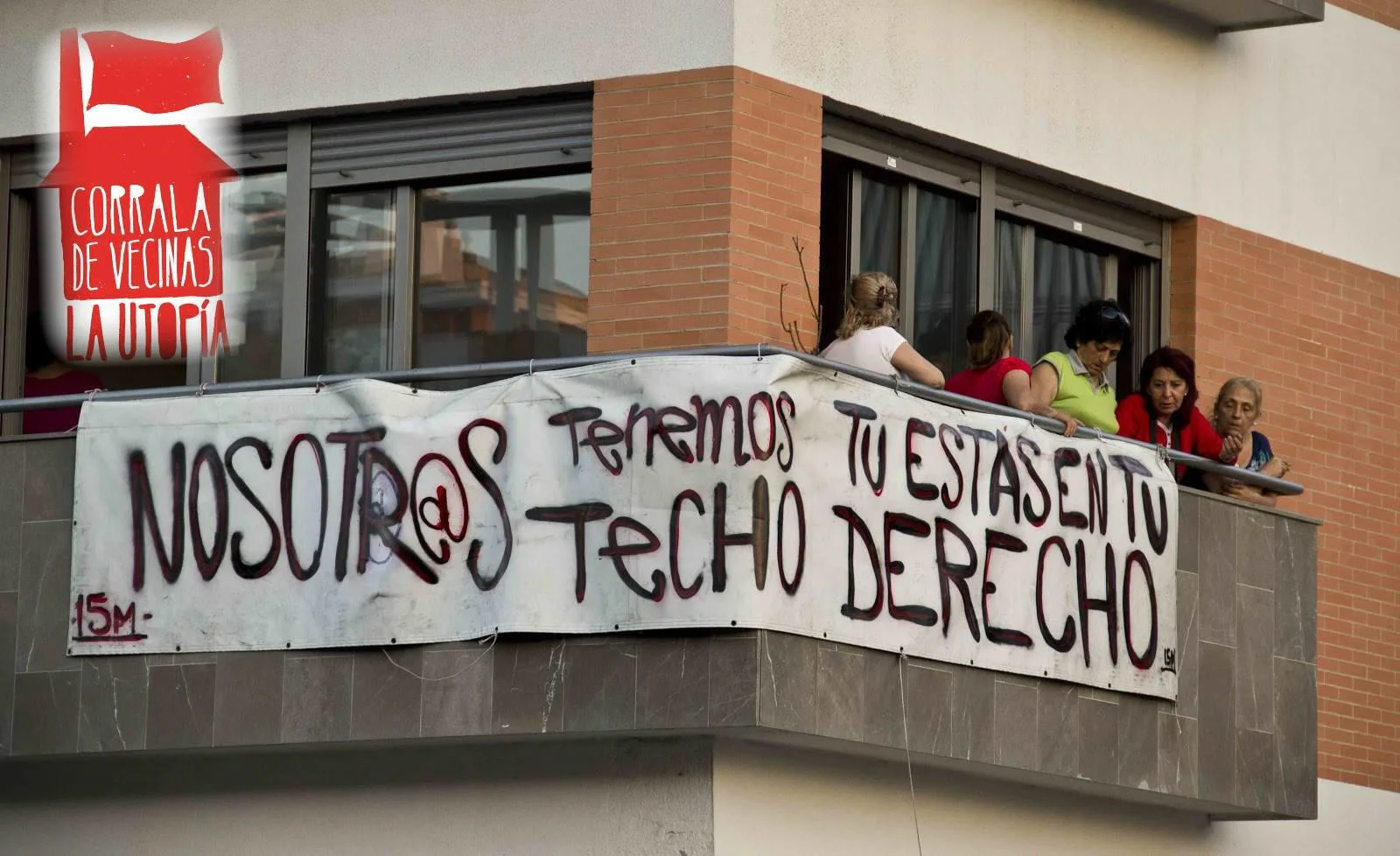 Women on a balcony with a protest banner