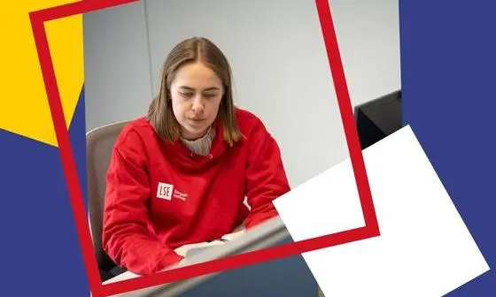 Girl wearing a red LSE EI Hoodie looking at her computer