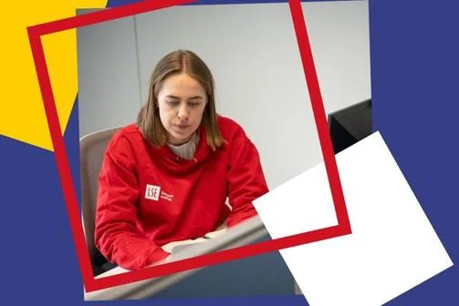 Girl wearing a red LSE EI Hoodie looking at her computer