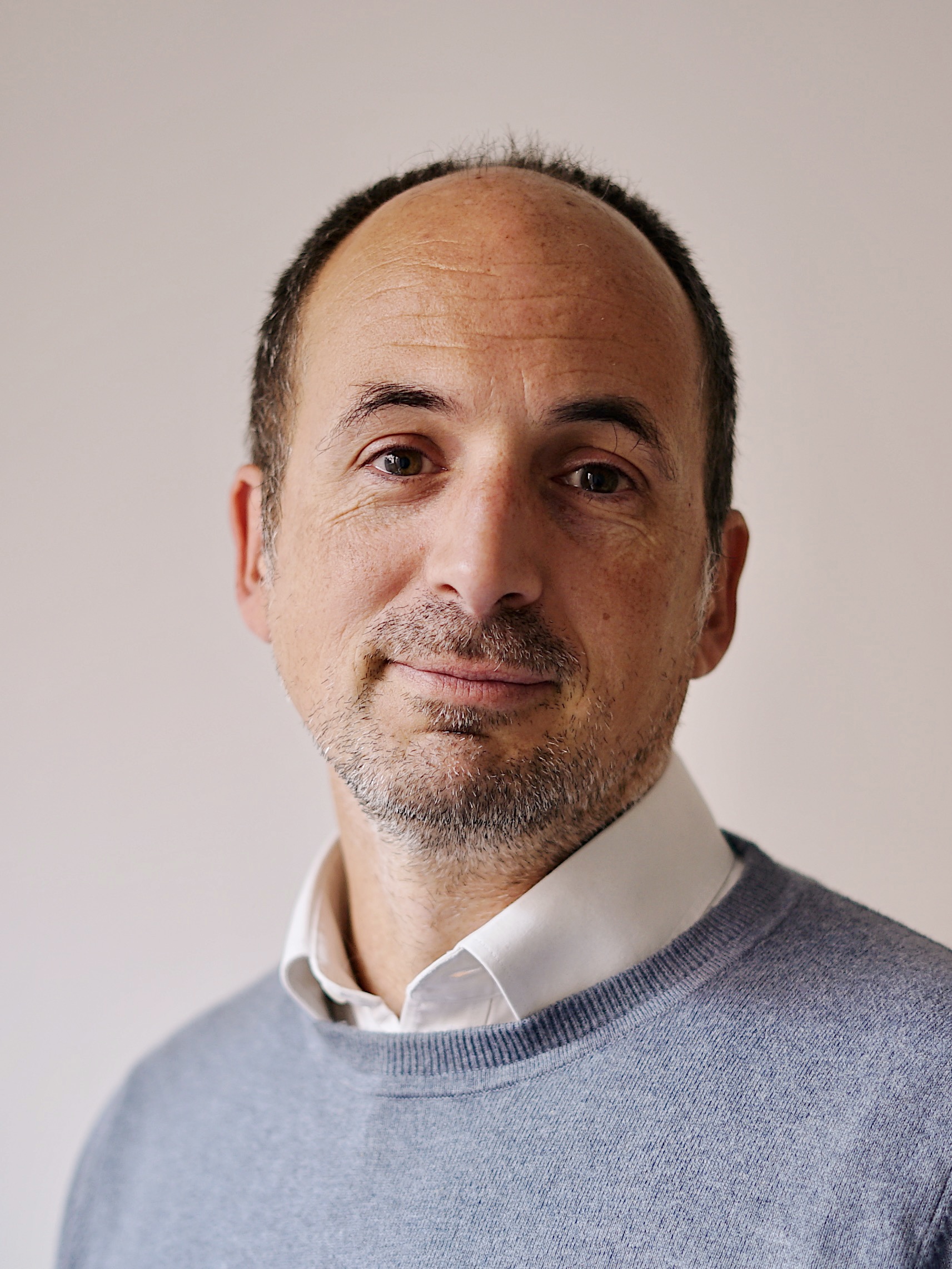 Dan Gardiner headshot wearing a shirt and grey jumper