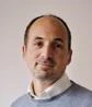 Dan Gardiner headshot wearing a shirt and grey jumper