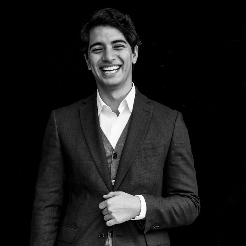 A black and white photo of Daniel Torres Checa. He is wearing a suit and smiling.