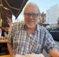 David Lowry smiling. He is wearing a blue shirt and glasses.