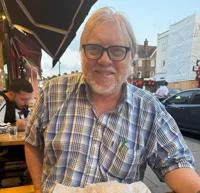 David Lowry smiling. He is wearing a blue shirt and glasses.