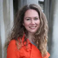 Professor Sara Houston - smiling wearing an orange coat