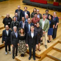 A cohort of executive education participants standing together and smiling at the camera