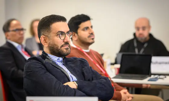 Man with glasses and arms crossed looks on