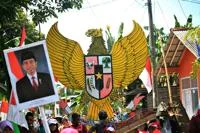 People gathered in the street, holding Indonesian national symbol.