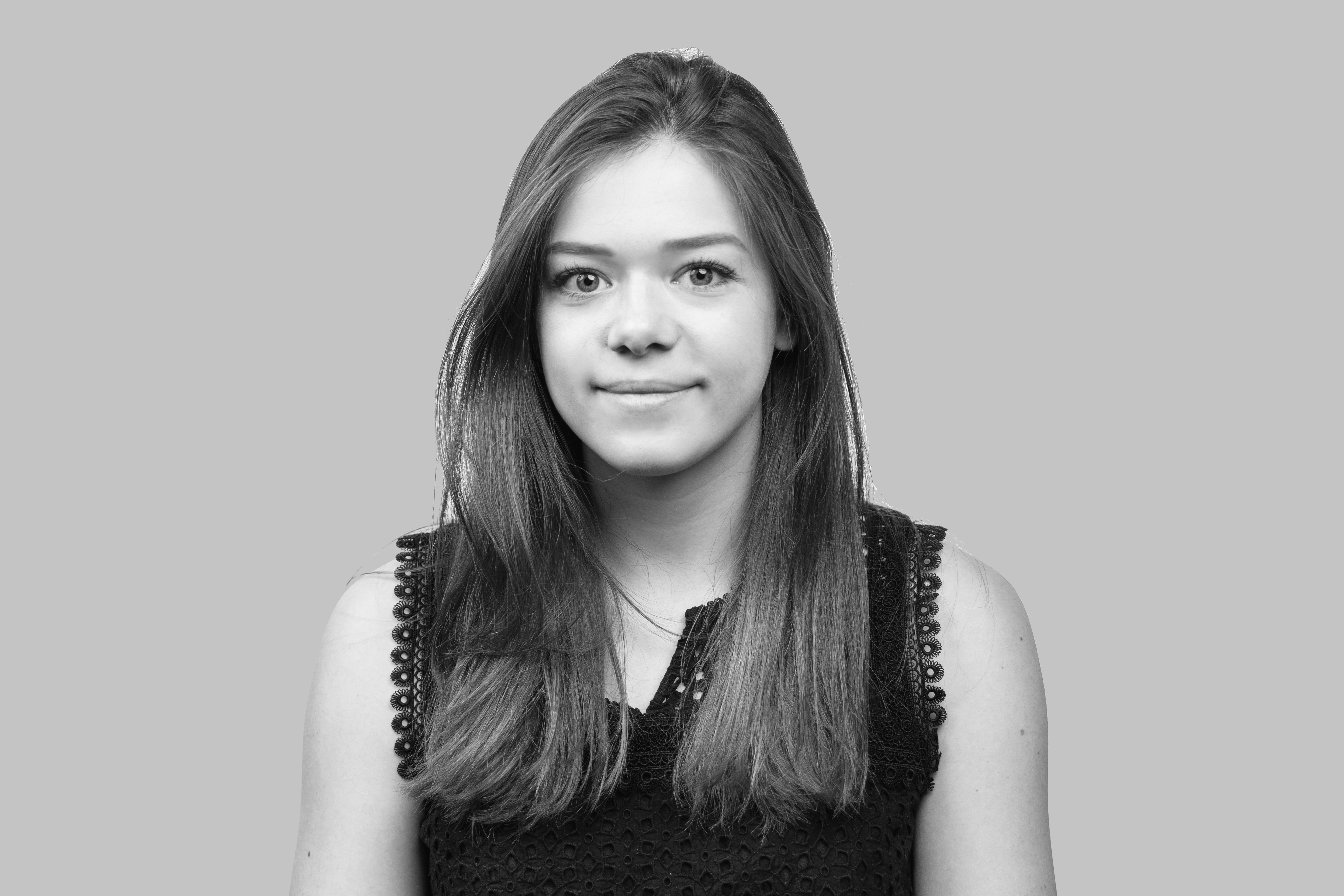 A black and white image of Emily Tadgell. She is looking at the camera and smiling.