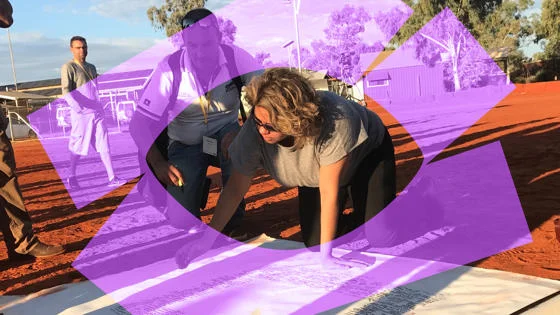 A woman on the floor looking at a large piece of paper.