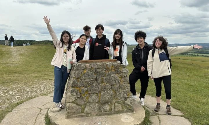 students standing at the top of a hill waving and smiling