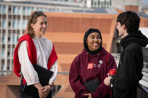 Three students standing together laughing